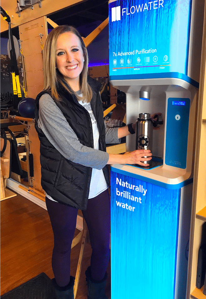Female business owner using filtered water dispenser for office