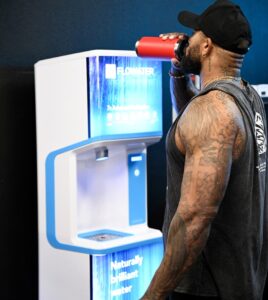 male athlete standing next to FloWater Refill Station drinking water