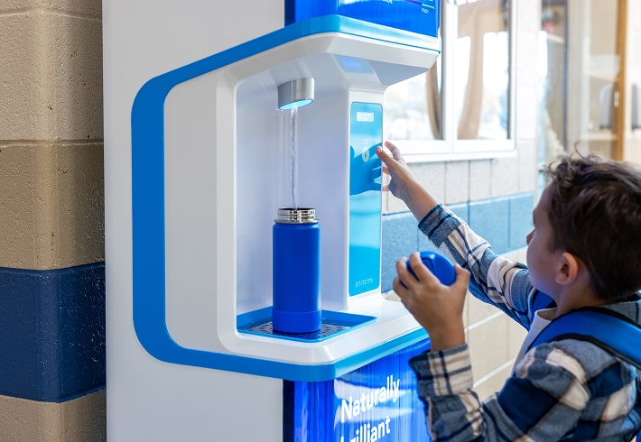 young student refilling his water bottle with a flowater refill station