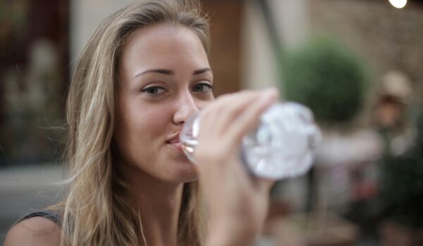 woman drinking water from plastic bottle