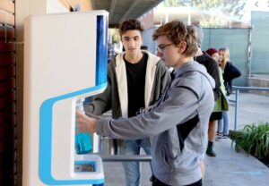two male students using flowater refill station at a school