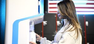 female athlete using FloWater refill station at a gym to refill water bottle