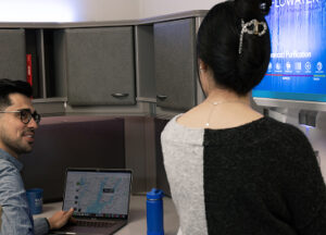 two people at desk near flowater refill station