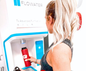 woman using flowater refill station at a gym